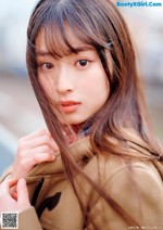 A woman with long brown hair wearing a brown coat.