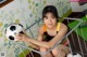 A young girl sitting in a crib holding a soccer ball.