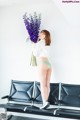 A woman standing on a bench holding a bunch of flowers.