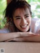 A smiling woman leaning on a couch with her arms crossed.