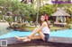 A woman sitting on the edge of a swimming pool.