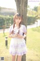 A young woman standing next to a tree in a park.